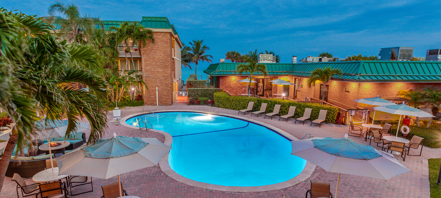 hotel pool at dawn with with umbrellas and chairs