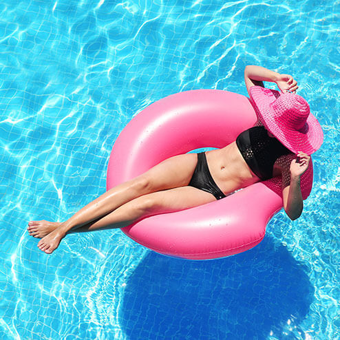 a woman in a pink hat is floating in a pool.