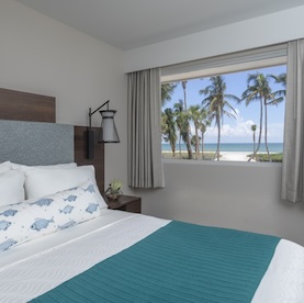 A bedroom with a view of the beach and ocean.