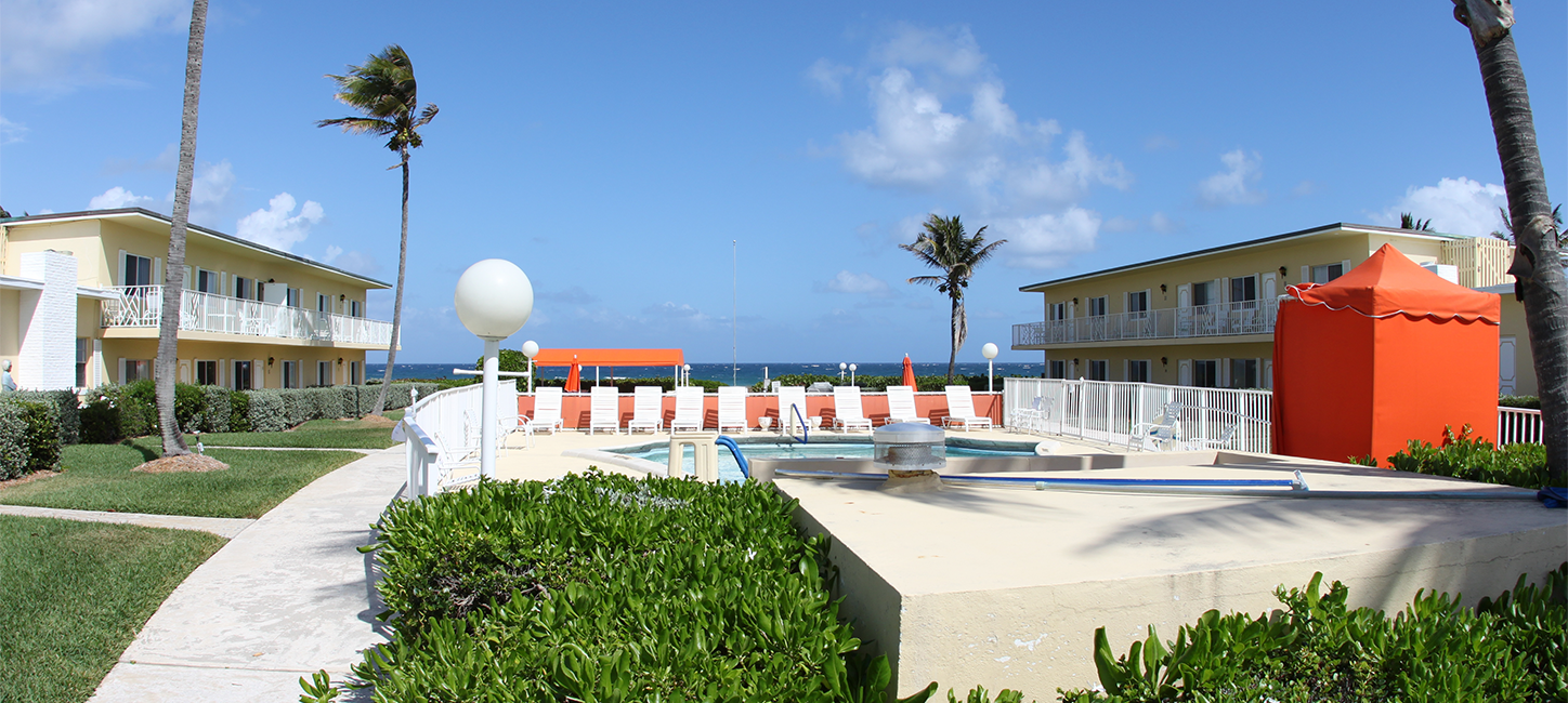 A pool with chairs and umbrellas in front of a building.
