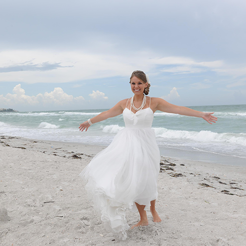 A woman in a white dress is running on the beach.