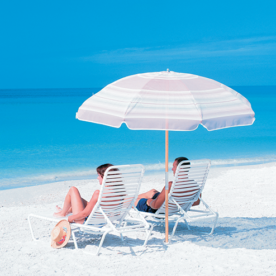 Two people sitting under an umbrella on a beach.