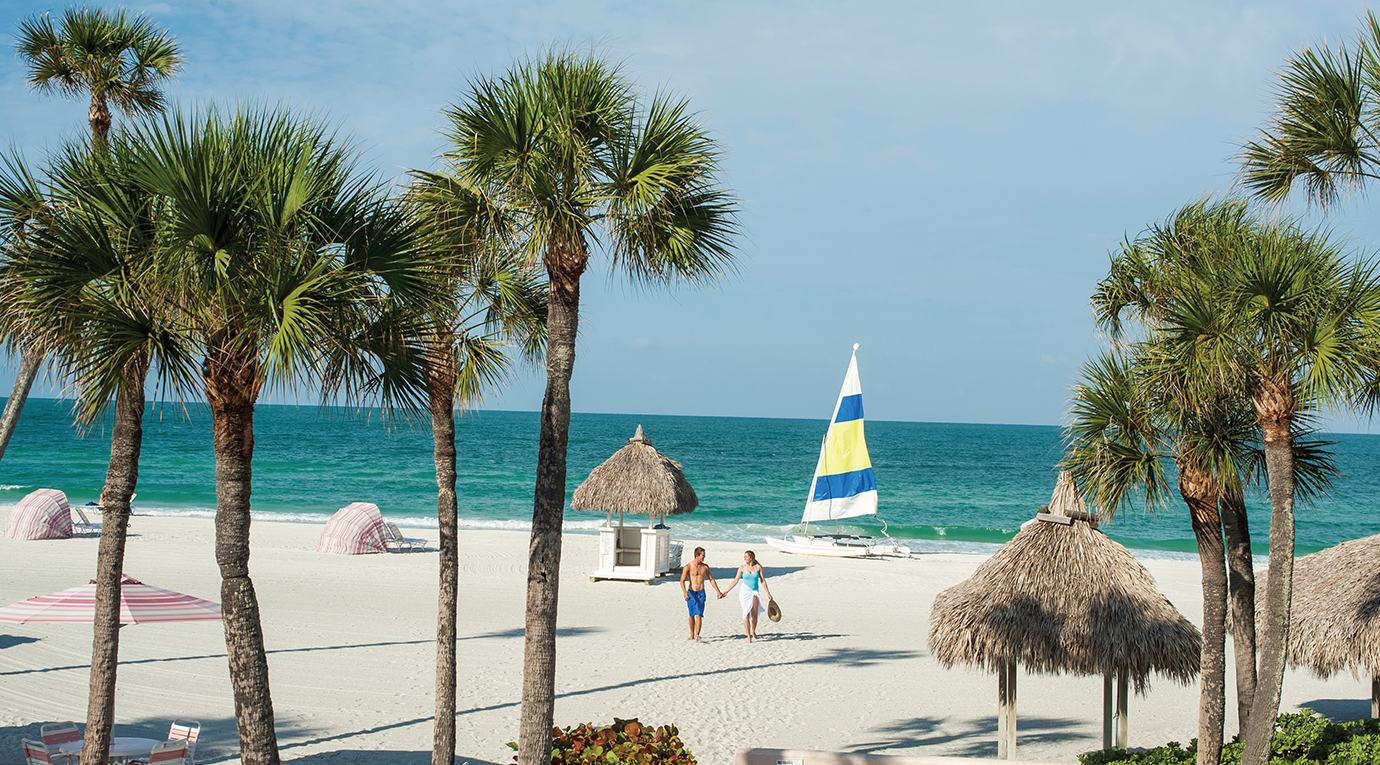 A beach with palm trees and umbrellas.