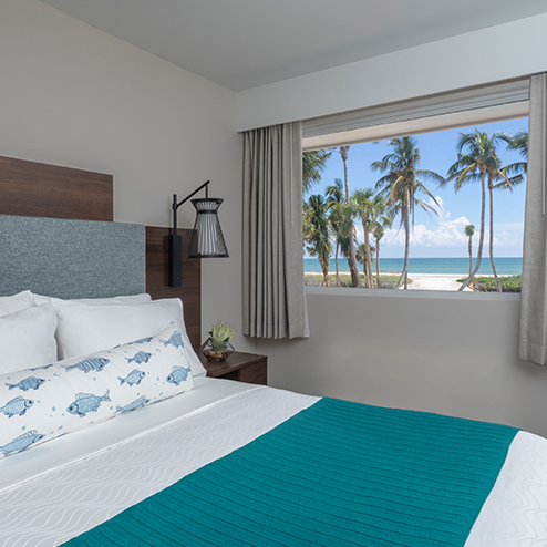 A bed in a room with a view of the ocean.