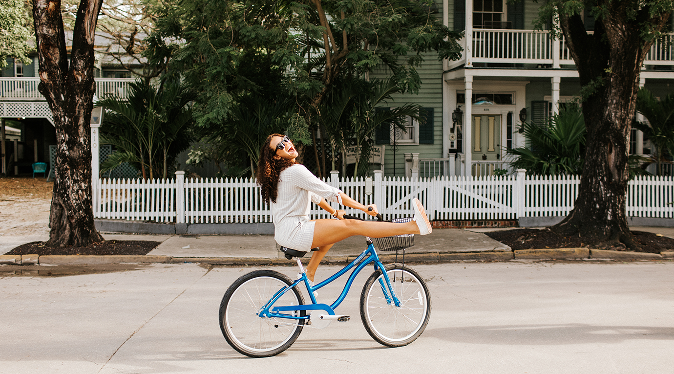 A woman riding a blue bicycle on a street.