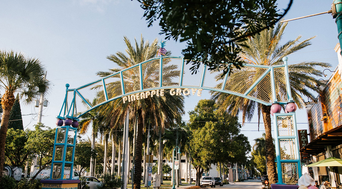 A street with palm trees and a blue archway.