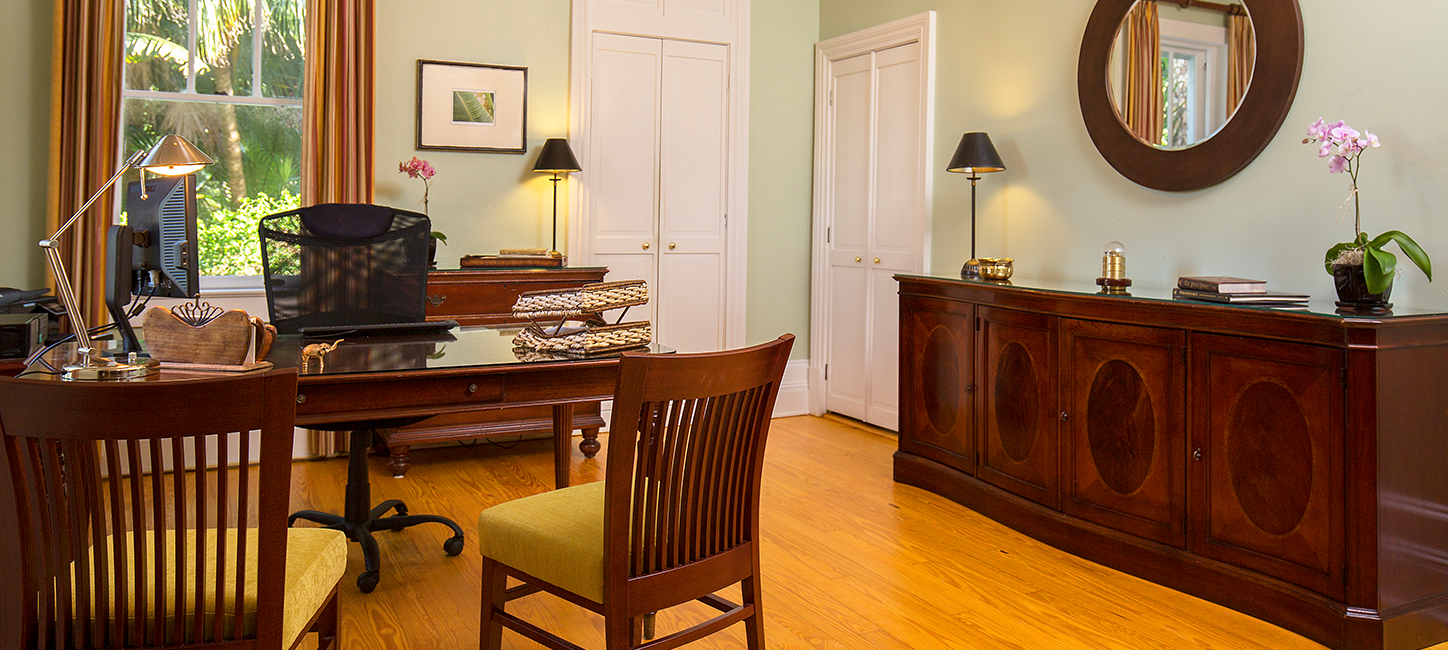 A room with a desk, chair and a mirror.