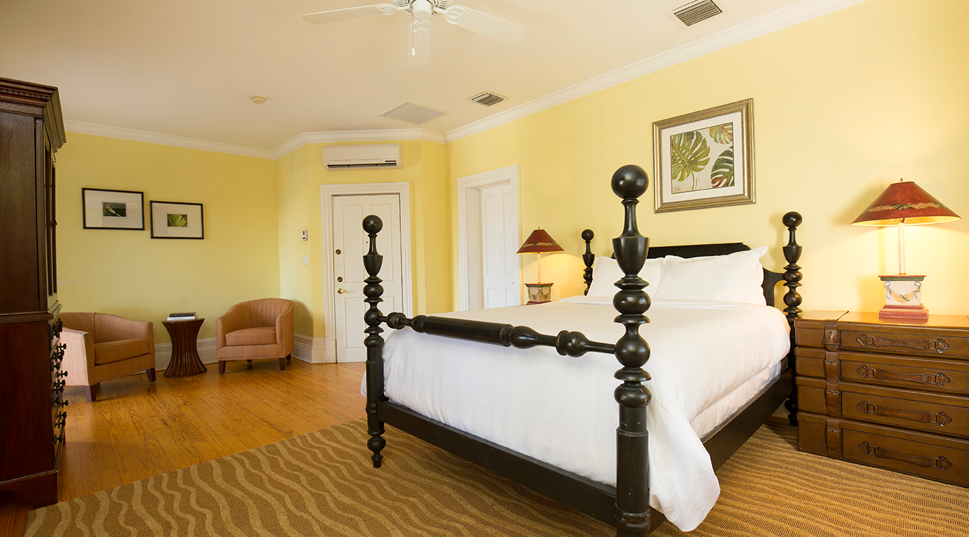 A yellow bedroom with a bed and a chair.