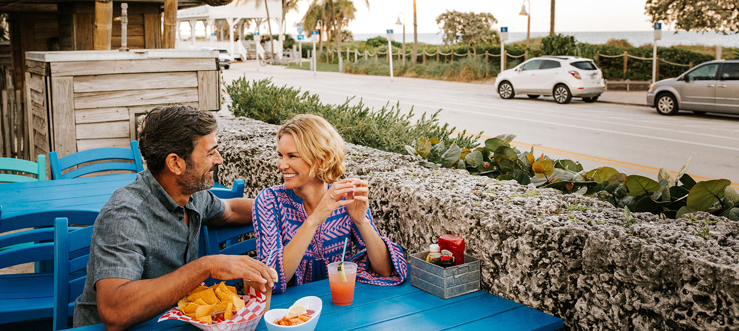 A man and woman sitting at a table eating chips and salsa.