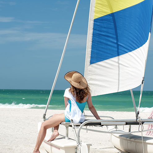A woman sitting on a sailboat on the beach.