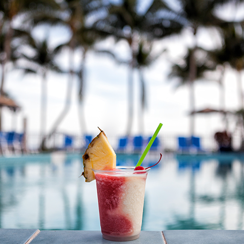 A drink on a table next to a pool.