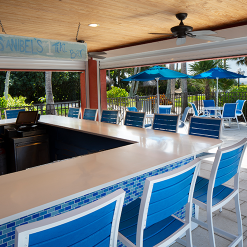 A blue tiled bar with blue chairs and umbrellas.