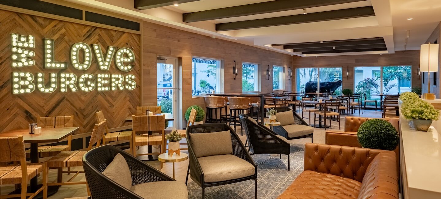 Interior of a modern burger restaurant with stylish wooden decor, comfortable seating, and a neon 